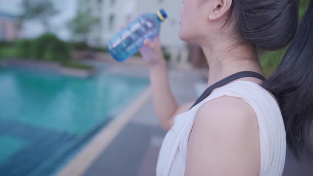 亚洲年轻健康的运动女性在锻炼期间休息饮用塑料瓶中的水，健康的生活方式，运动后的新鲜，口渴脱水视频素材