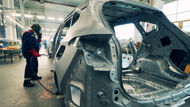 汽车厂工人正在焊接一辆未完工的汽车车身视频素材