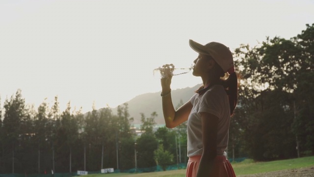 年轻女高尔夫球手在户外喝瓶子里的水视频素材