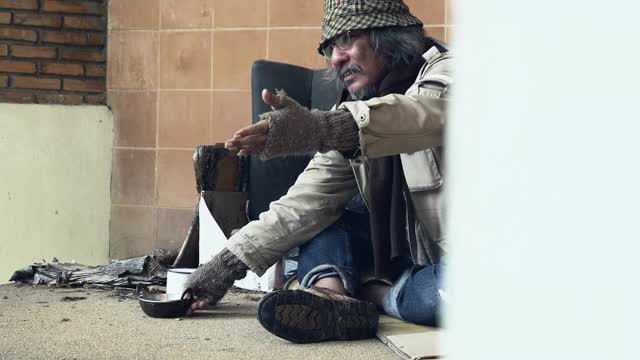 无家可归的人在街上拿着钱乞讨。城市概念中无家可归者的问题。视频下载