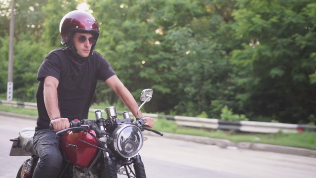 骑摩托车的人在黄昏的乡村公路上飞驰，咖啡车手摩托车冒险的生活方式视频素材