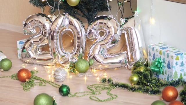 2021年的新年假期组成银气球。背景是圣诞树视频下载