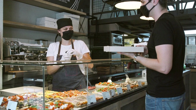 戴着防护口罩和手套的妇女给顾客外卖披萨盒视频素材
