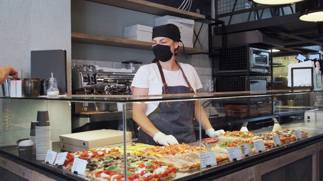 戴着防护面罩和手套的妇女给顾客外卖披萨视频素材
