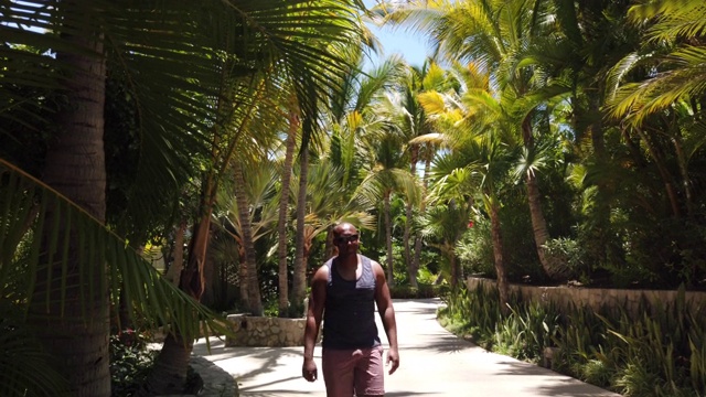 一个黑人走在热带天堂里。视频下载