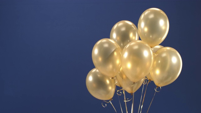 这个装饰元素——金色气球——出现在视频中，作为一个节日的惊喜:在蓝色背景下的情人节、生日、圣诞节或新年。视频素材