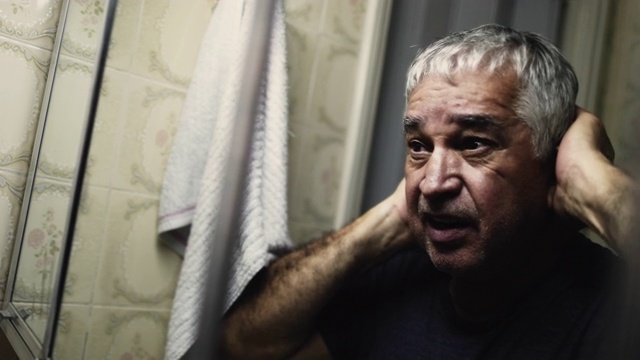 一个戏剧性的老人在黑暗中在浴室的镜子前受苦视频素材
