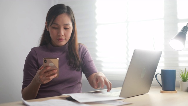 亚洲女性在家用智能手机在线支付账单视频素材