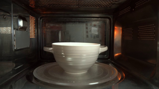 一个装有食物的陶瓷碗在微波炉中旋转加热视频下载
