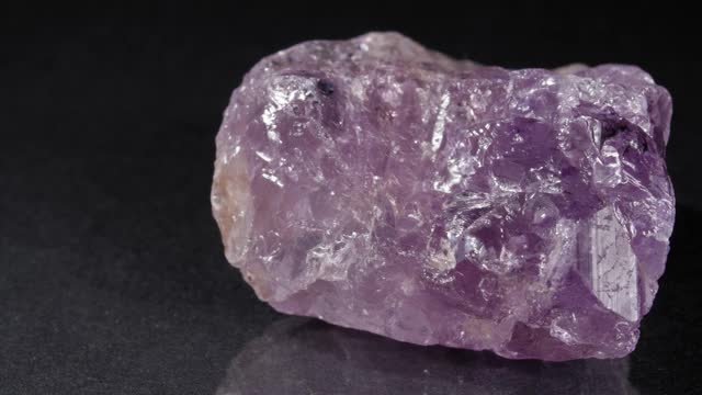 紫色水晶在一个黑暗的背景特写。天然石材，紫色矿物。视频下载