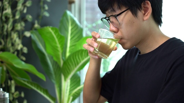 在家里工作的男人喝着用玻璃杯盛着的绿茶视频下载