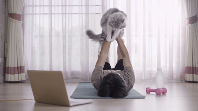 健康的年轻人做运动与他的猫在家里视频素材