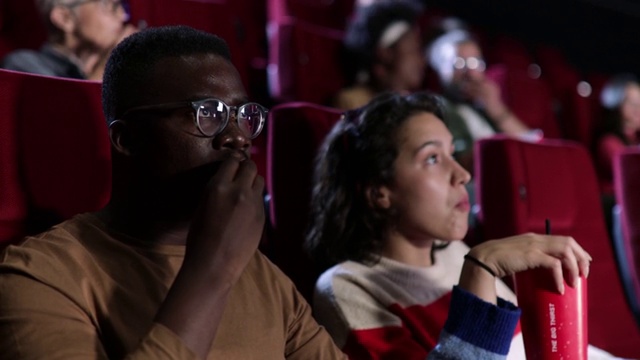 一个女孩和她的非裔美国朋友在电影院看一部严肃的电影视频下载