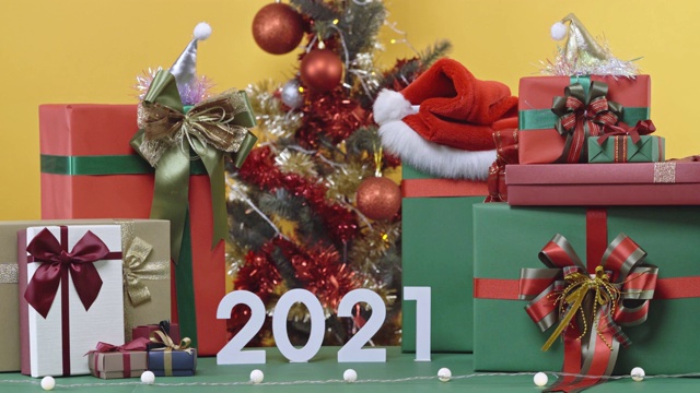 装饰圣诞树和礼物礼盒。圣诞快乐，新年快乐，黄色背景上的2021模型。4 k决议。视频素材