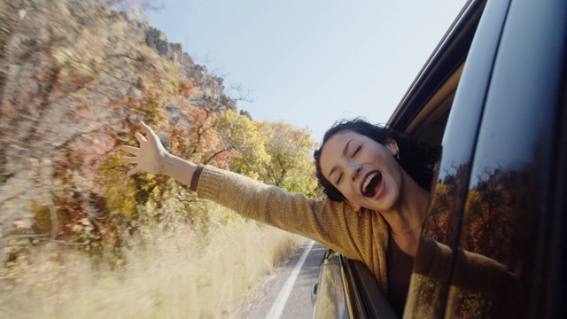 年轻女子在山里的公路旅行中玩得很开心视频素材