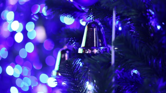 圣诞树上的圣诞钟声以闪闪发光的灯光为背景从模糊到聚焦视频素材