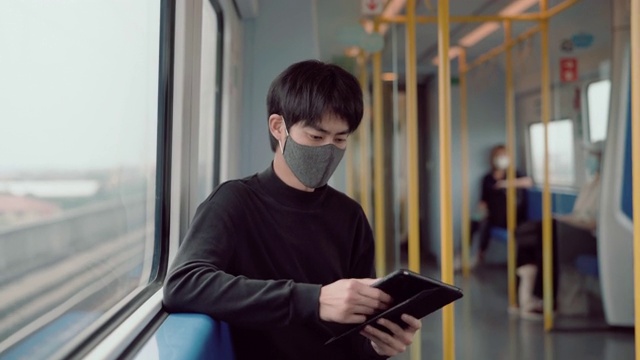 公共交通工具上的年轻商人戴着口罩和平板电脑。视频素材