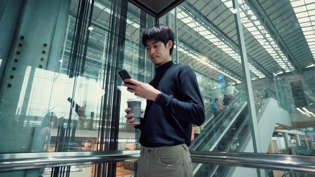 一个自信的男人在出差时乘坐电梯进入机场的走廊视频素材
