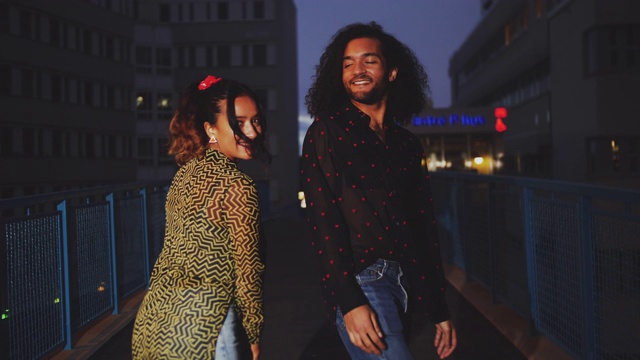 手持拍摄的幸福的夫妇走在城市的人行桥上的夜晚视频素材