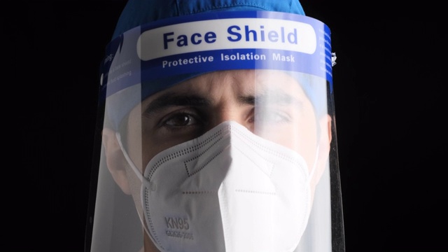 沉思疲倦的年轻男性医护人员看着镜头，戴着n95防护面罩和面罩视频素材