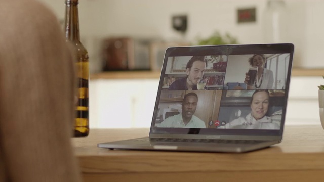 女性使用视频通话技术在厨房桌子上和朋友在笔记本电脑上享受饮料视频素材