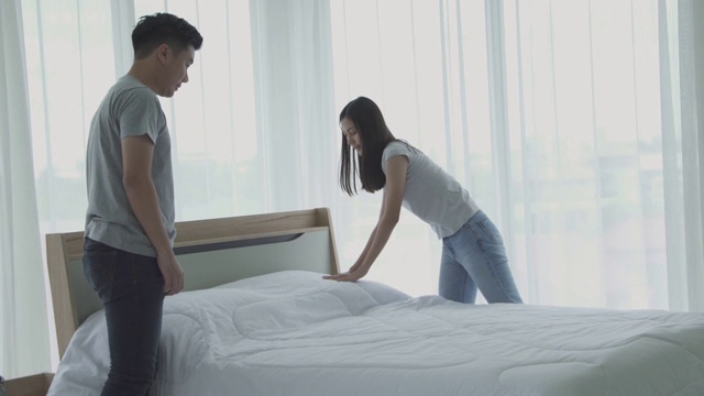 一对穿着睡衣的夫妇在早上整理床铺。视频素材