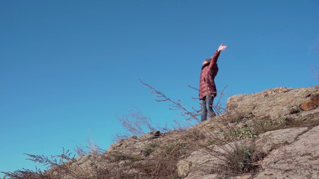 一个年轻的女游客在山顶上。她在欣赏美丽的景色。视频素材