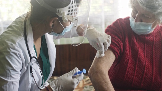 女性保健人员在家中为老年妇女注射疫苗。视频下载