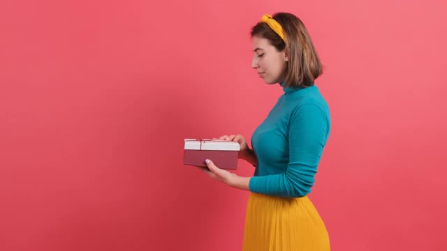 一个快乐的女人打开礼物盒的特写在红色的背景视频素材
