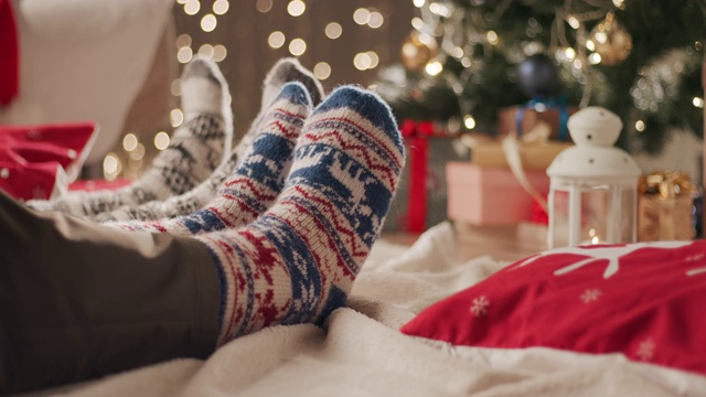 两个人坐在地板上的毯子上，在圣诞袜里移动他们的脚视频下载