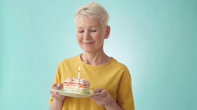 老女人吹灭生日蛋糕上的蜡烛视频素材