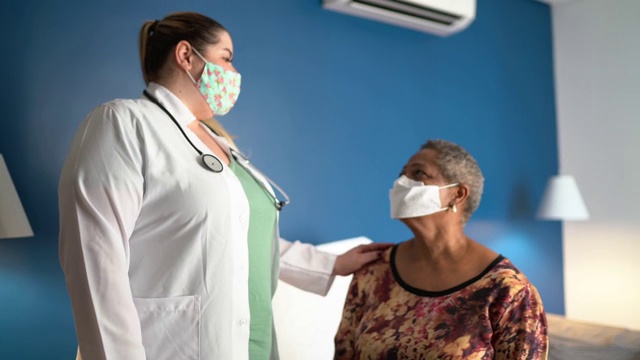 医生照顾老年妇女病人的医疗访问在她的家里-使用口罩视频素材