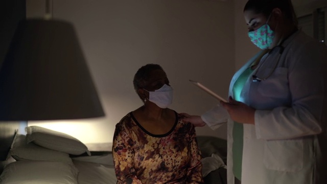 医生在老年妇女病人家中与她交谈-使用口罩视频素材