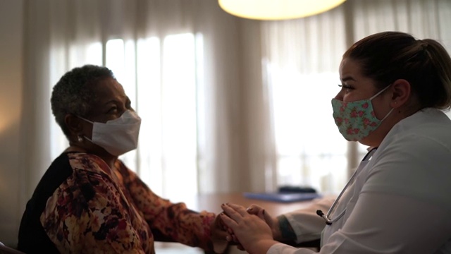 医生照顾老年妇女病人的医疗访问在她的家里-使用口罩视频素材
