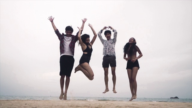 一群亚洲朋友在夏天的海滩上一起跳的慢镜头视频下载