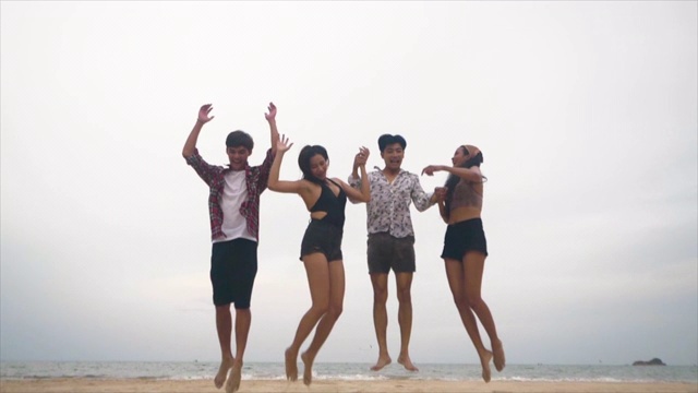 一群亚洲朋友在夏天的海滩上一起跳的慢镜头视频素材