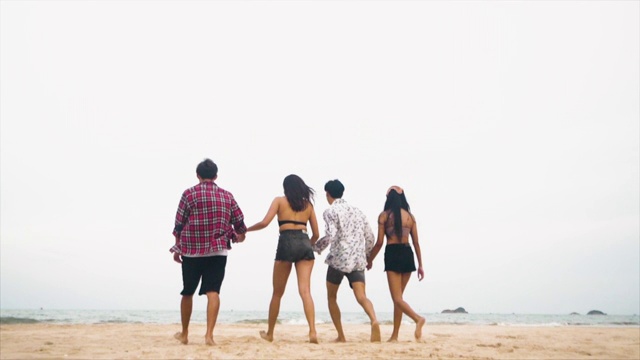 一群亚洲朋友在夏天的海滩上一起跳的慢镜头视频素材