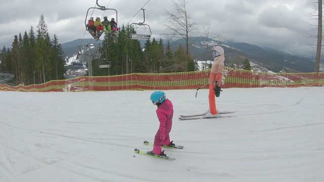 那孩子正和他母亲一起滑雪。视频素材