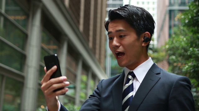 快乐的亚洲商人使用无线耳机进行电话会议视频素材