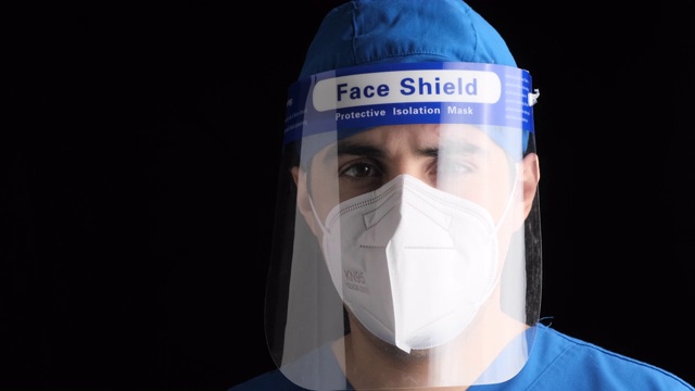 沉思疲倦的年轻男性医护人员看着镜头，戴着n95防护面罩和面罩视频素材