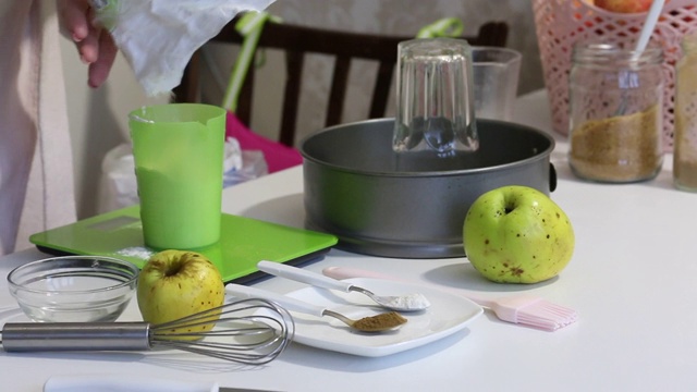 一位妇女用厨房秤称面粉。制作夏洛特的工具和配料。和苹果派。视频下载