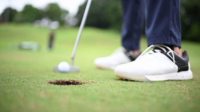 亚洲华人男子高尔夫球击到高尔夫球场的高尔夫洞的特写镜头视频素材