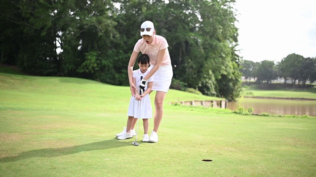 亚洲华人家长周末在高尔夫球场教女儿打高尔夫球视频下载