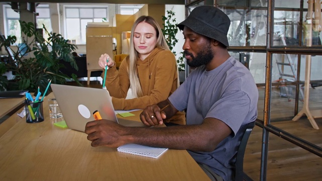 年轻的办公室经理与非裔美国客户交谈，用慢镜头向他展示笔记本电脑上的营销策略视频素材