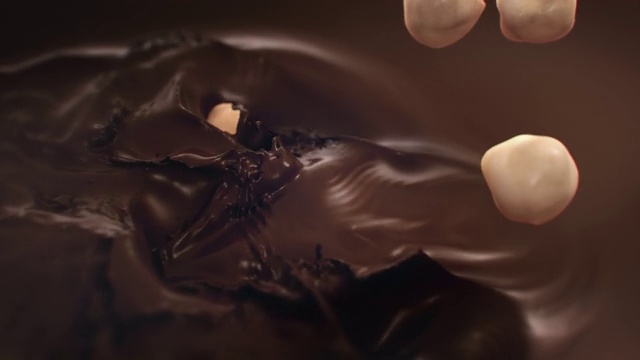 4K超级慢动作，榛子溅入液态黑巧克力视频素材
