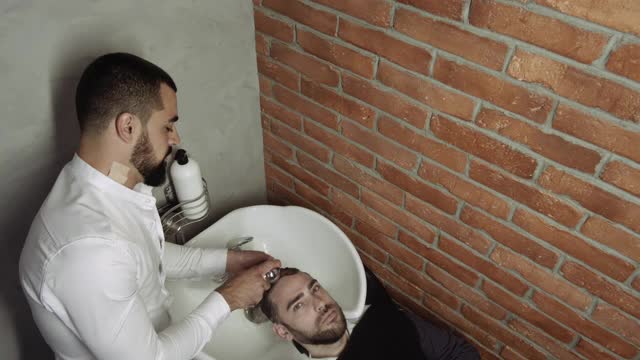 一个身份不明的男性理发师的手在剪一个男人的头发视频素材