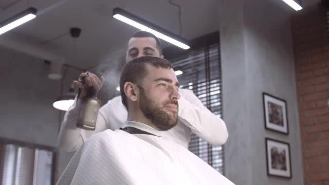 一个身份不明的男性理发师的手在剪一个男人的头发视频素材