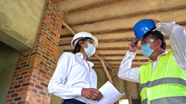 一位拉丁女工程师与她的工人交谈，并展示如何建造一座房子。这发生在covid - 19期间视频下载
