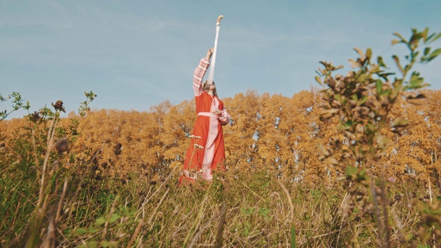 身穿红色民族服装的金发女子站在赛场上，手持宝剑击剑视频下载