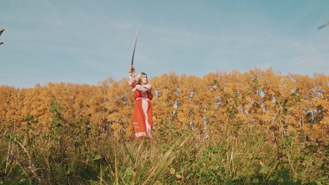 身穿红色长裙的金发女子站在黄色场地上，手持两把剑击剑视频下载